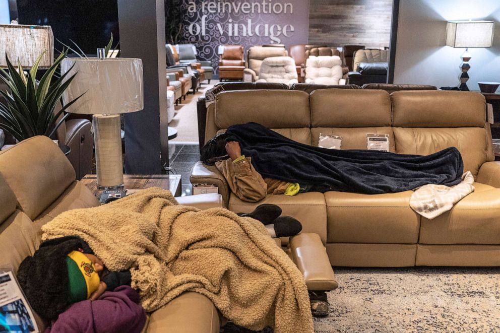 PHOTO: People sleep on couches while taking shelter at Gallery Furniture store which opened its door and transformed into a warming station after winter weather caused electricity blackouts, Feb. 18, 2021, in Houston, Texas.