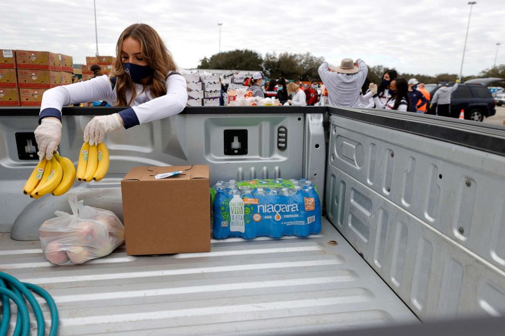 PHOTO: A Houston Texans cheerleader places bananas into the bed of a truck food during the Houston Food Bank food distribution at NRG Stadium, Feb. 21, 2021, in Houston, Texas.