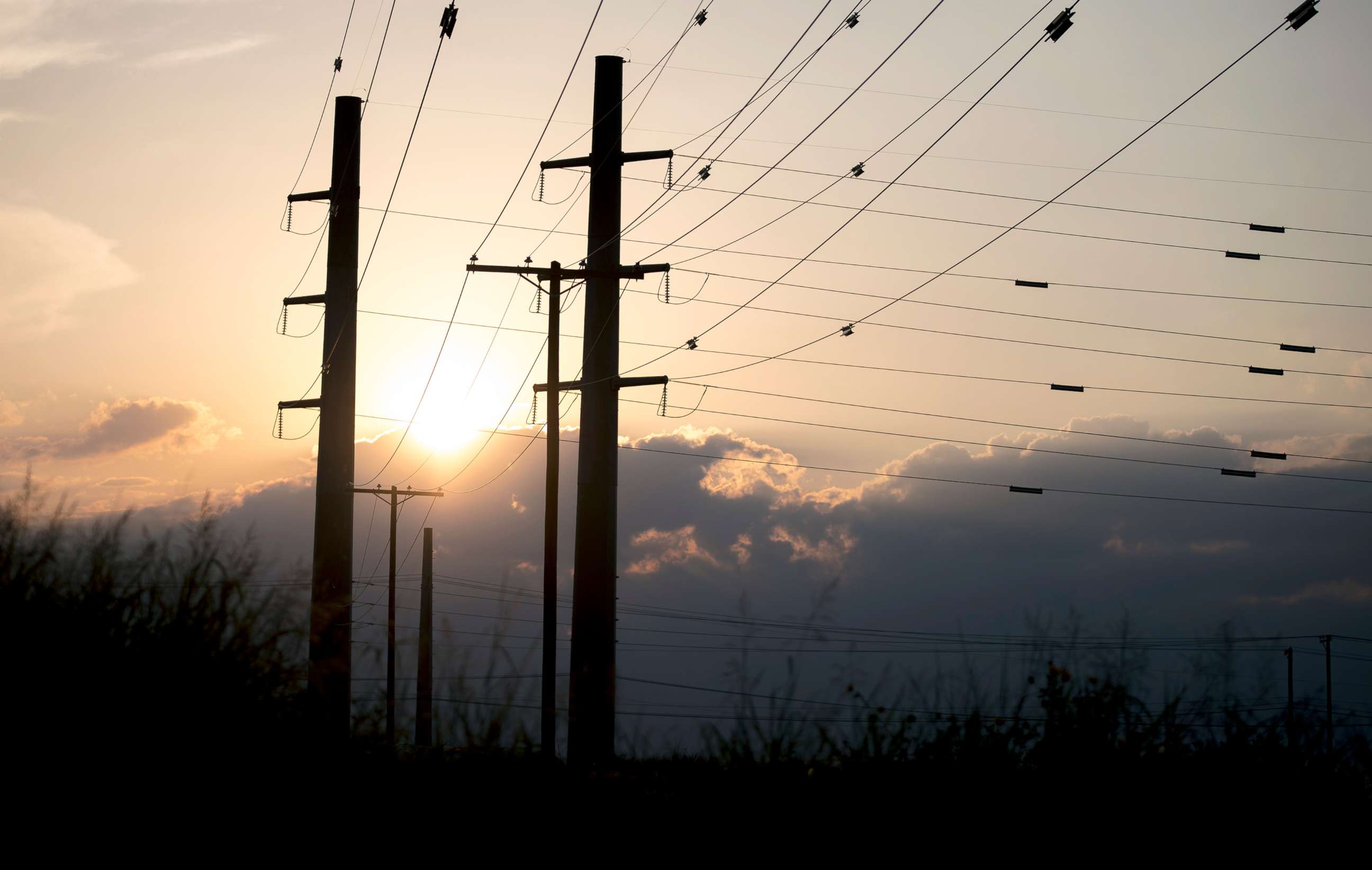PHOTO: The sun sets behind power transmission lines in Houston, Texas, July 11, 2022.