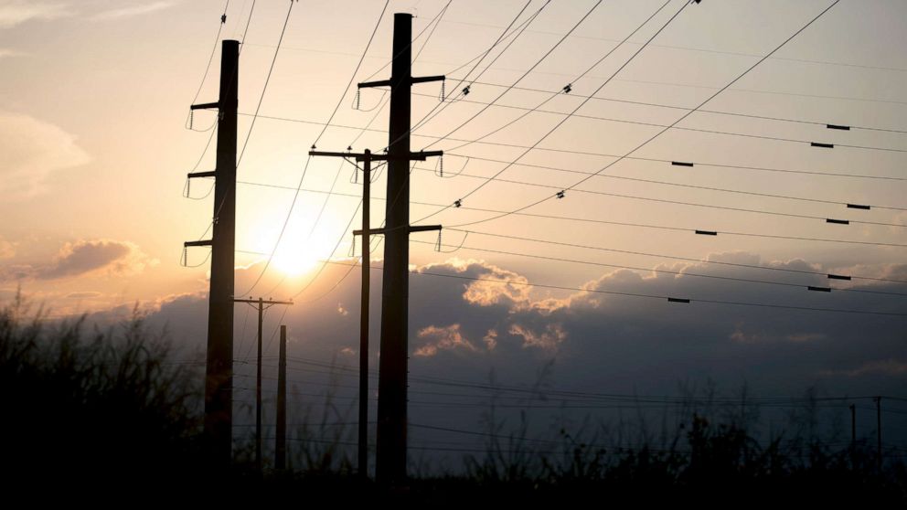PHOTO: The sun sets behind power transmission lines in Houston, Texas, July 11, 2022.