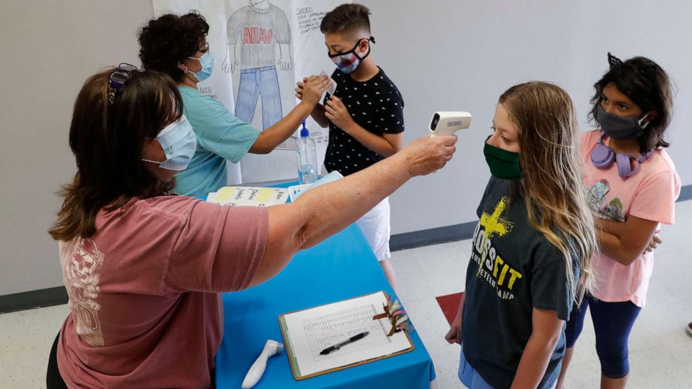 PHOTO: Amid concerns of the spread of COVID-19, science teachers Ann Darby, left, and Rosa Herrera check-in students before a summer STEM camp at Wylie High School, July 14, 2020, in Wylie, Texas.