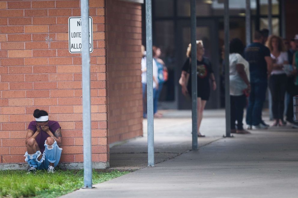 PHOTO: People gather by the Barnett Intermediate School where parents are gathering to pick up their children following a shooting at Santa Fe High School on May 18, 2018, in Santa Fe, Texas.