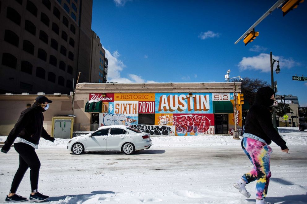 PHOTO: Pedestrians walk on along a snow-covered street on Feb. 15, 2021, in Austin, Texas.