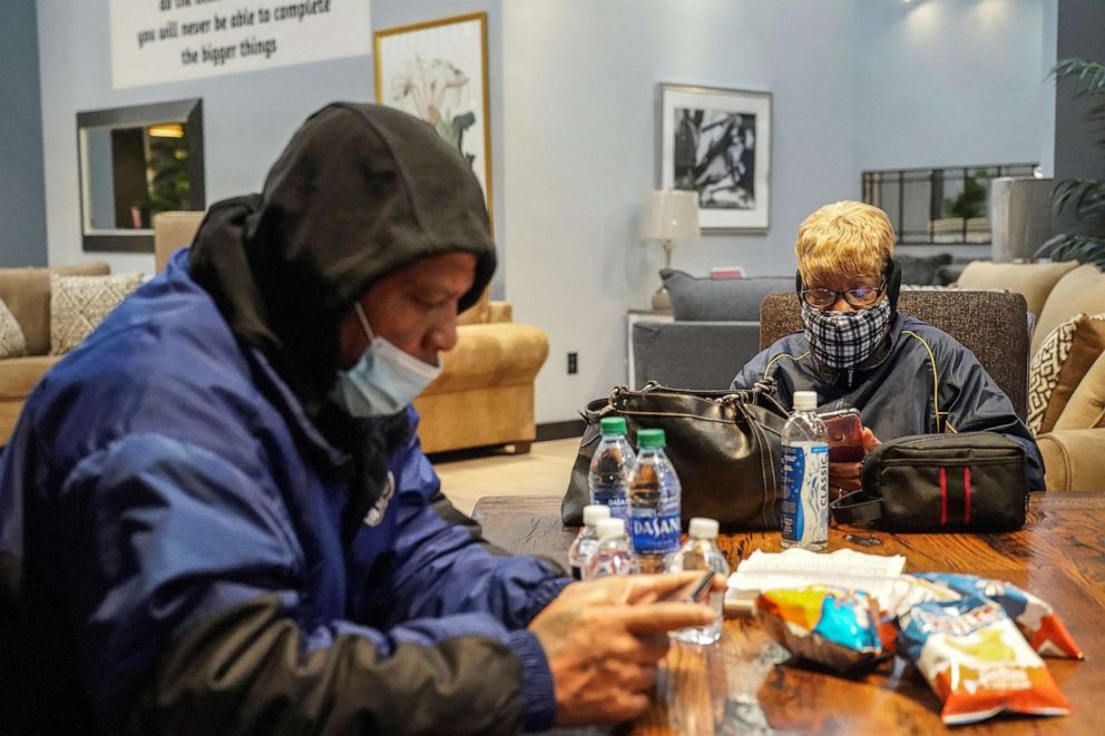 Jason Miszell and his wife Debra Bracey check their smartphones while taking a shelter at Gallery Furniture store which opened its door and transformed into a warming station after winter weather caused electricity blackouts in Houston, Feb. 17, 2021.