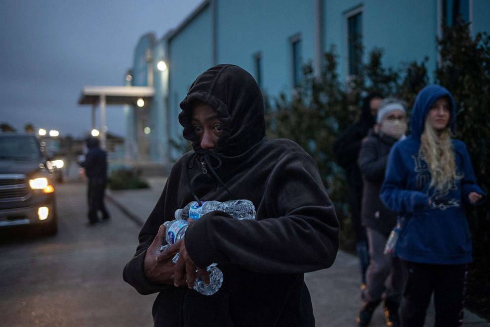PHOTO: A woman carries bottled water she received from a warming center and shelter after record-breaking winter temperatures, as local media report most residents are without electricity, in Galveston, Texas on Feb. 17, 2021.