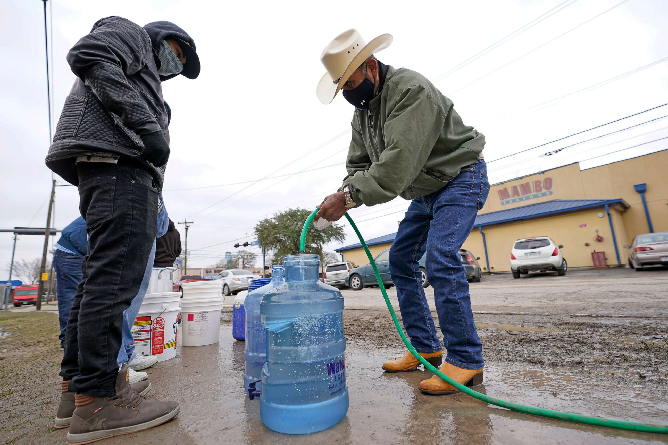 PHOTO: Leovardo Perez, right, fills a water jug using a hose from a public park water spigot, Feb. 18, 2021, in Houston.