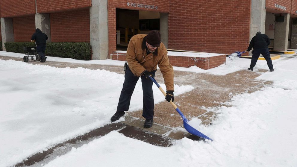 PHOTO: Bank of America Plaza employees shovel ice and snow from the sidewalks as a cold weather front moves through Dallas, Jan. 31, 2023.