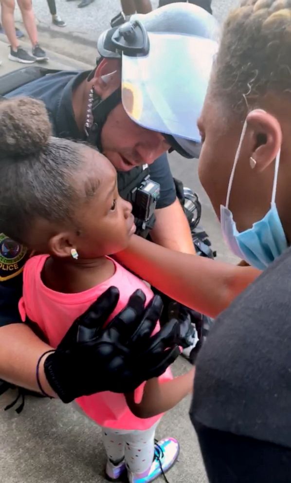 PHOTO: A police officer comforts a little girl during a protest in Houston, Texas, June 2, 2020.