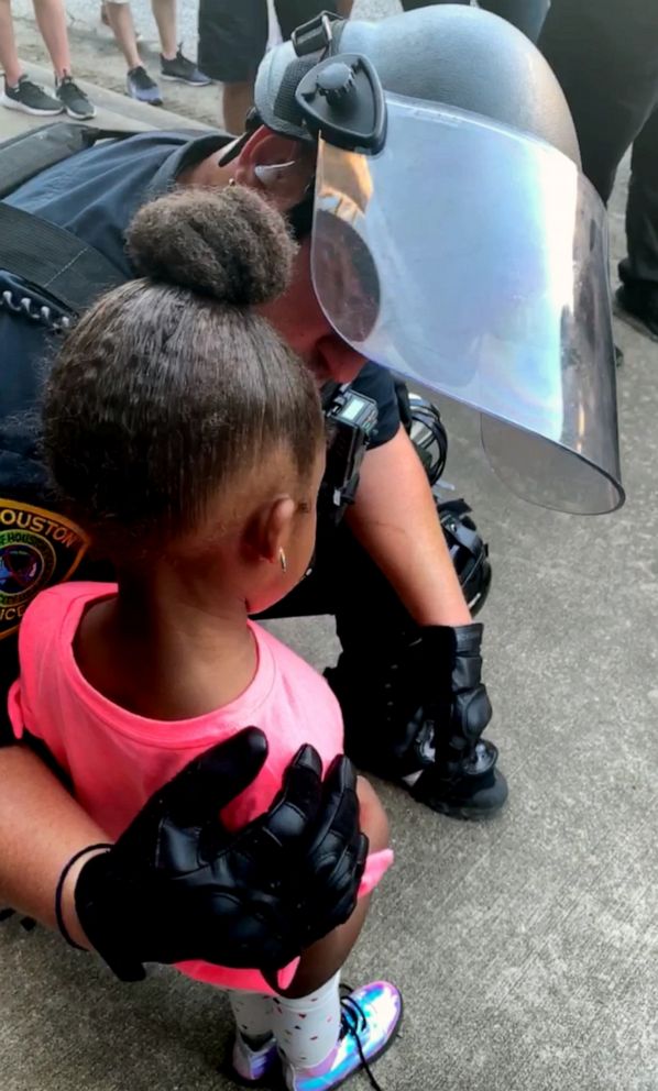 PHOTO: A police officer comforts a little girl during a protest in Houston, June 2, 2020.