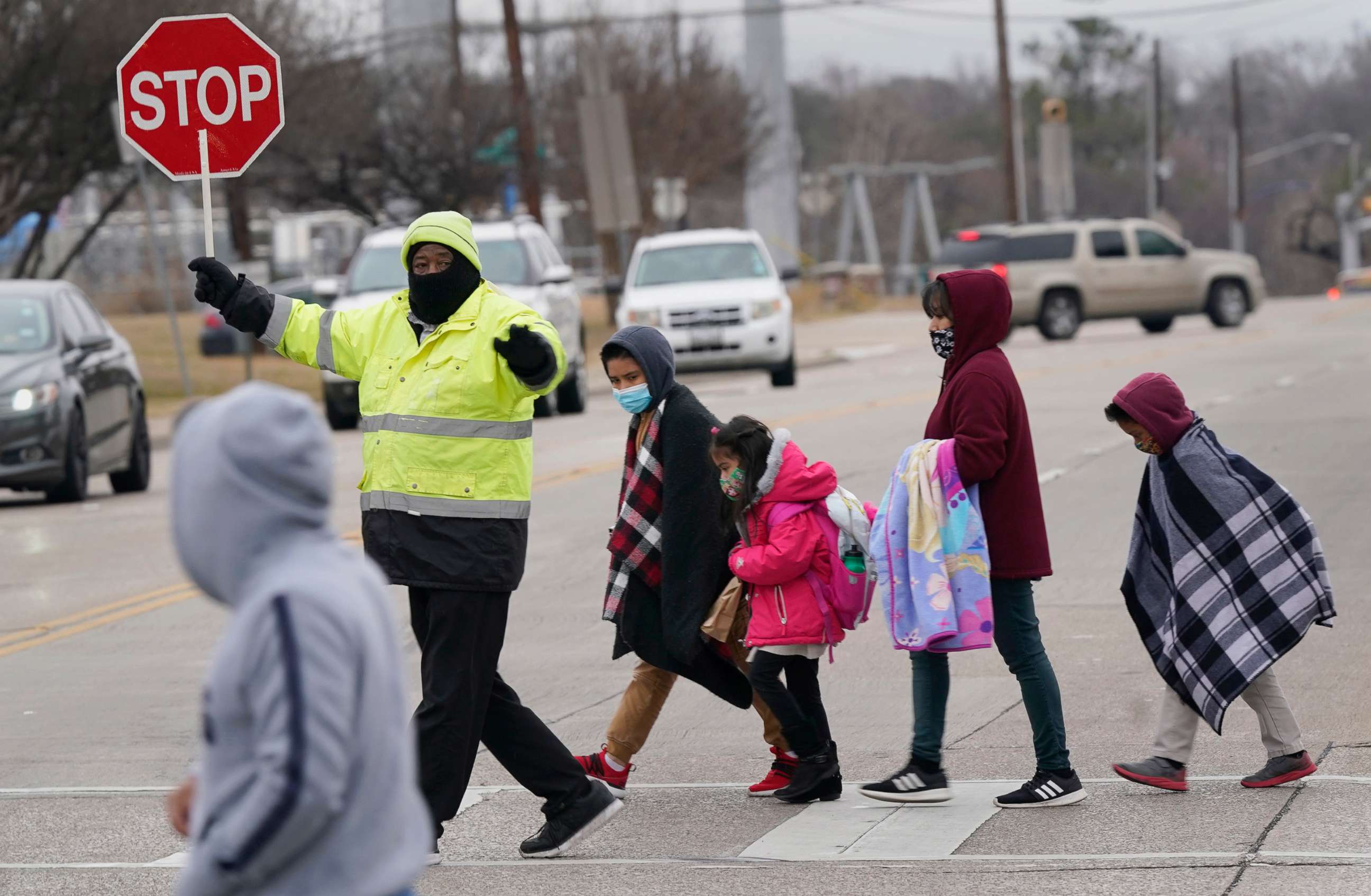 PHOTO: With winter weather coming, crossing guard Willie McCree, stops traffic for a family to cross the street in Dallas, Feb. 2, 2022. North Texas school districts called off classes for the next two days in anticipation of winter weather.