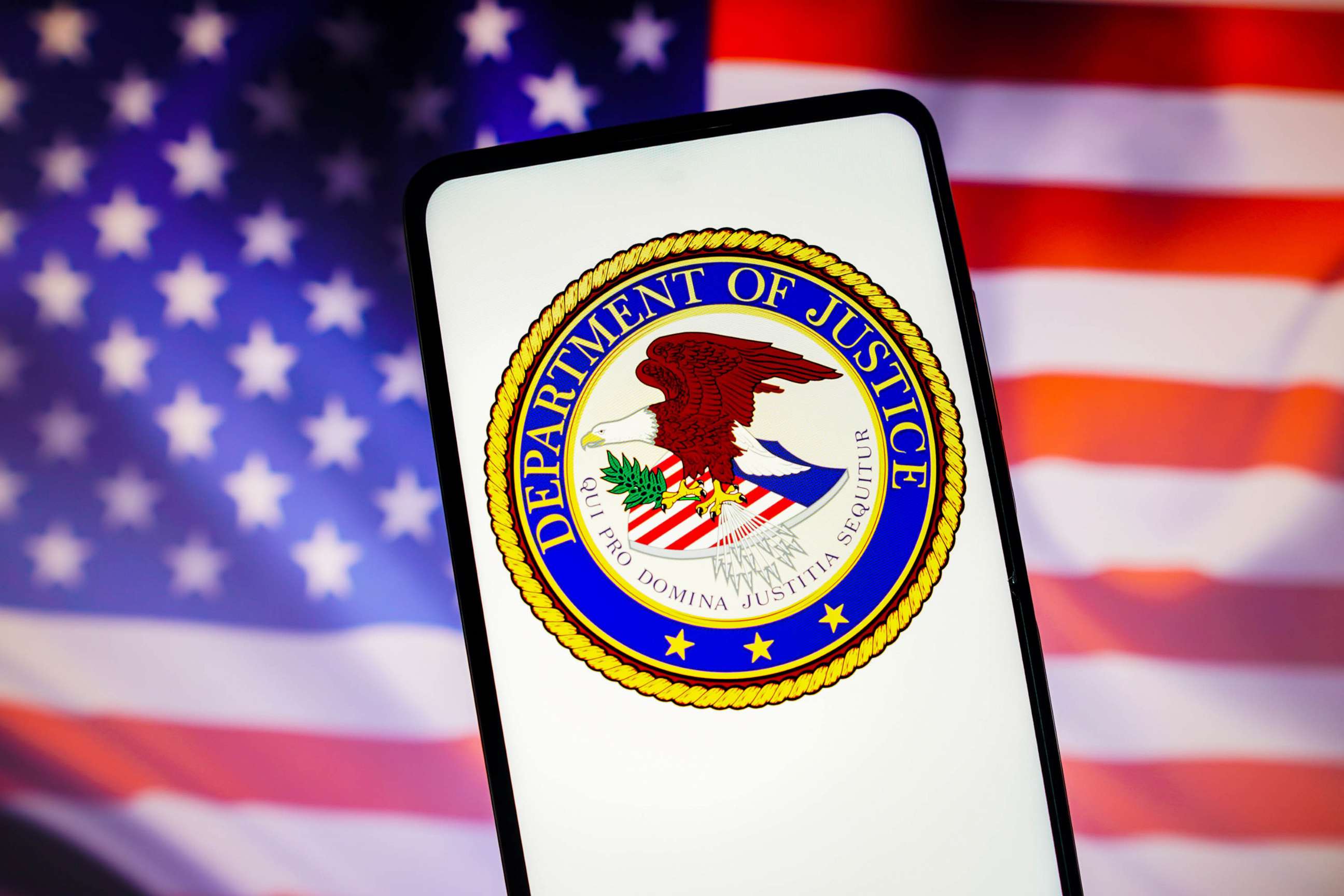 PHOTO: FILE - In this photo illustration, the United States Department of Justice (DOJ) logo is displayed on a smartphone screen with a United States flag in the background.