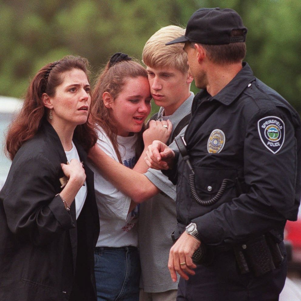 PHOTO: Students hug as a police officer walks past outside of Thurston High School in Springfield, Ore., May 21, 1998, after a student opened fire with a semiautomatic rifle in the high school cafeteria.
