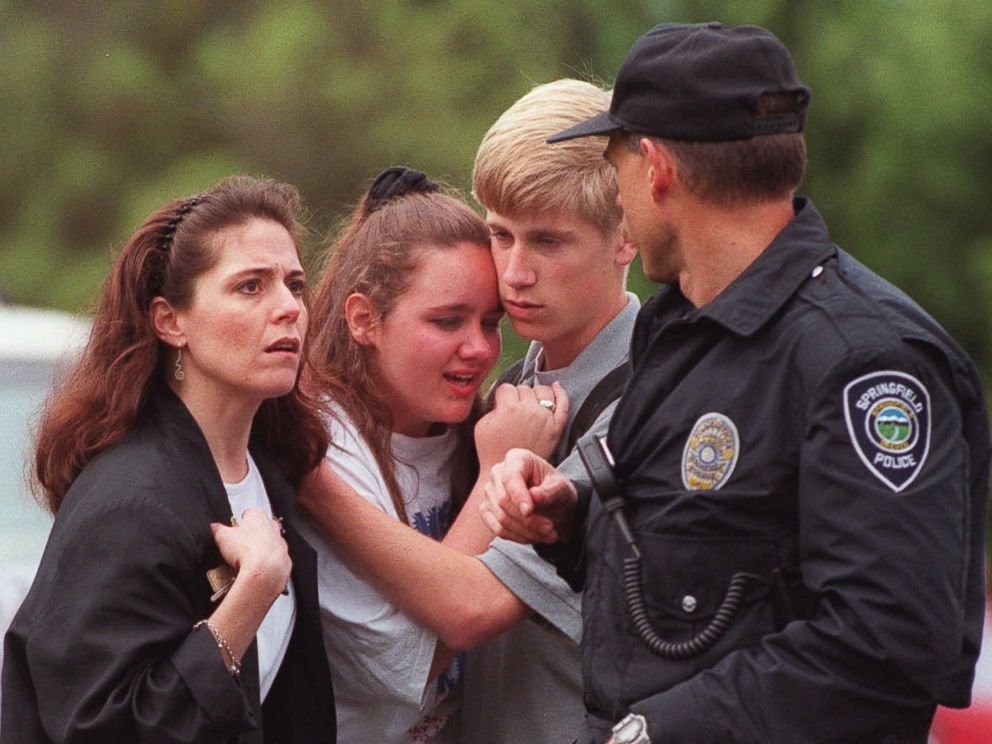 PHOTO: Students hug as a police officer walks past outside of Thurston High School in Springfield, Ore., May 21, 1998, after a student opened fire with a semiautomatic rifle in the high school cafeteria.
