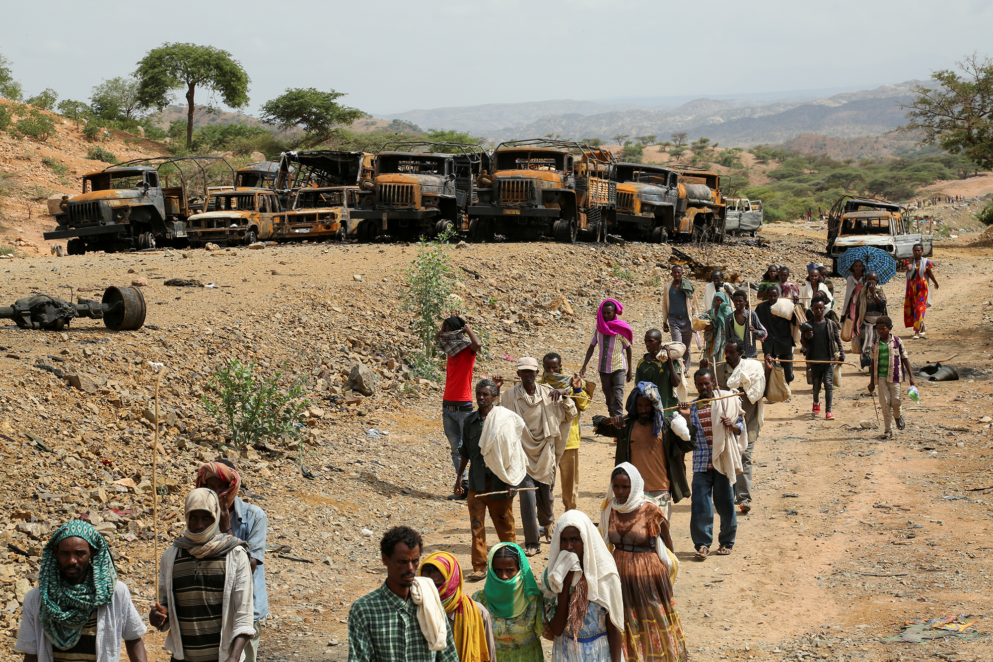 PHOTO: Villagers return from a market to Yechila town in south central Tigray walking past scores of burned vehicles, in Tigray, Ethiopia, July 10, 2021.