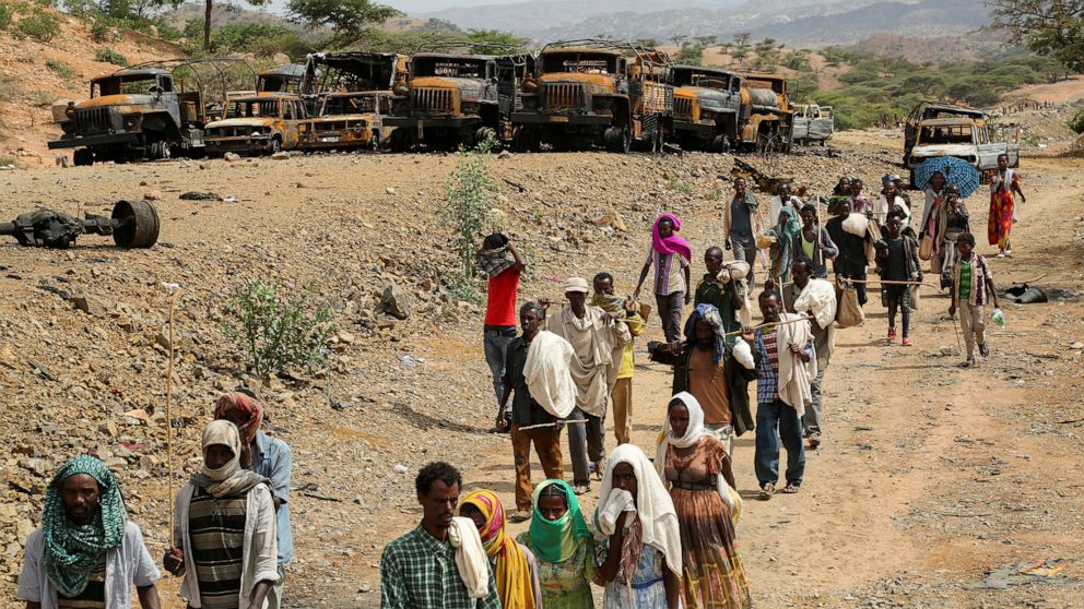 PHOTO: Villagers return from a market to Yechila town in south central Tigray walking past scores of burned vehicles, in Tigray, Ethiopia, July 10, 2021.