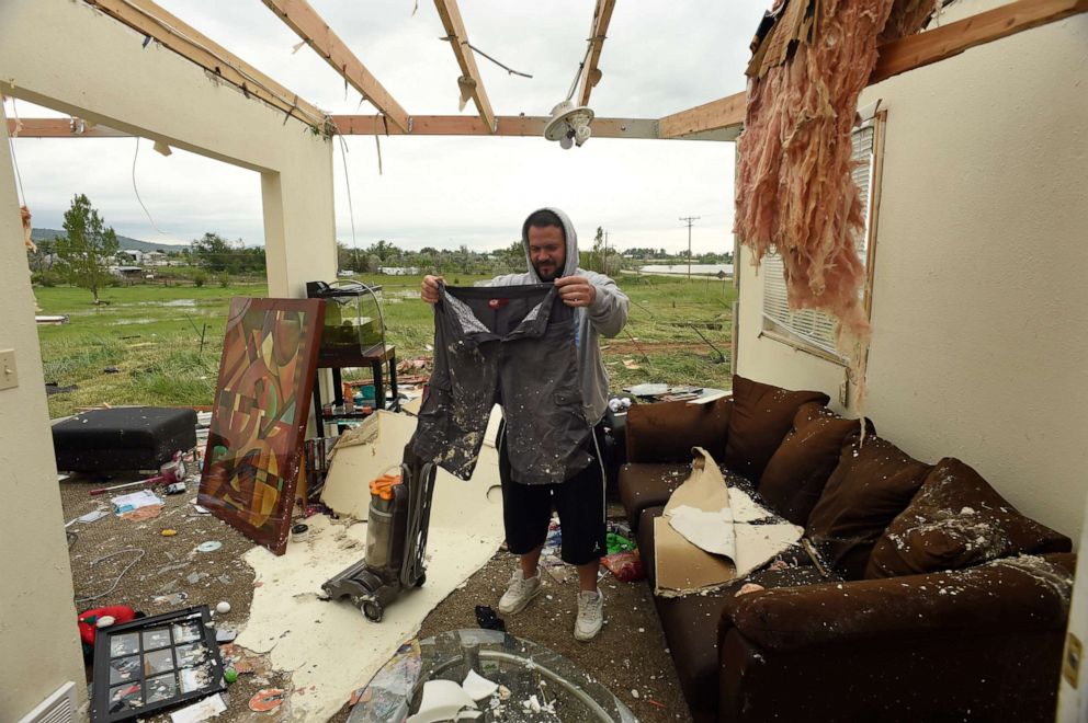 PHOTO: Homeowner Brandon Scott picks up a pair of  wet shorts inside the living room of his home that was heavily damaged after a tornado ripped through it near Longmont, Colo., June 5, 2015.