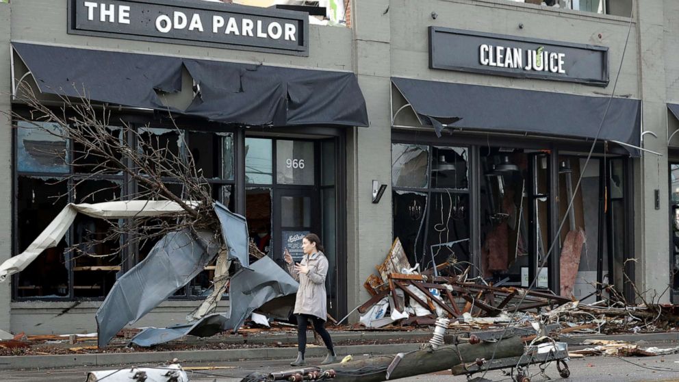 PHOTO: A woman walks past buildings damaged by a tornado, March 3, 2020, in Nashville, Tenn.