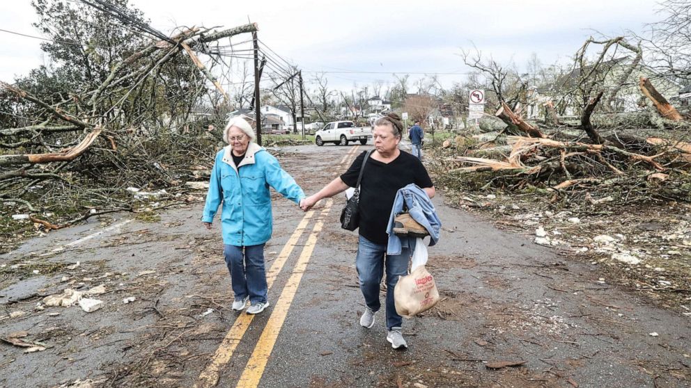 PHOTO: Two women make their way down a debris filled street in Coweta County, Ga., on March 26, 2021, after a tornado moved through the area.