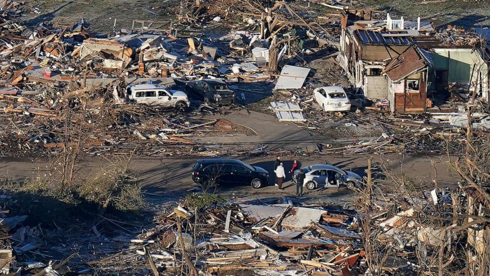 PHOTO: People stand amidst destruction from a recent tornado in downtown Mayfield, Ky., Dec. 12, 2021.