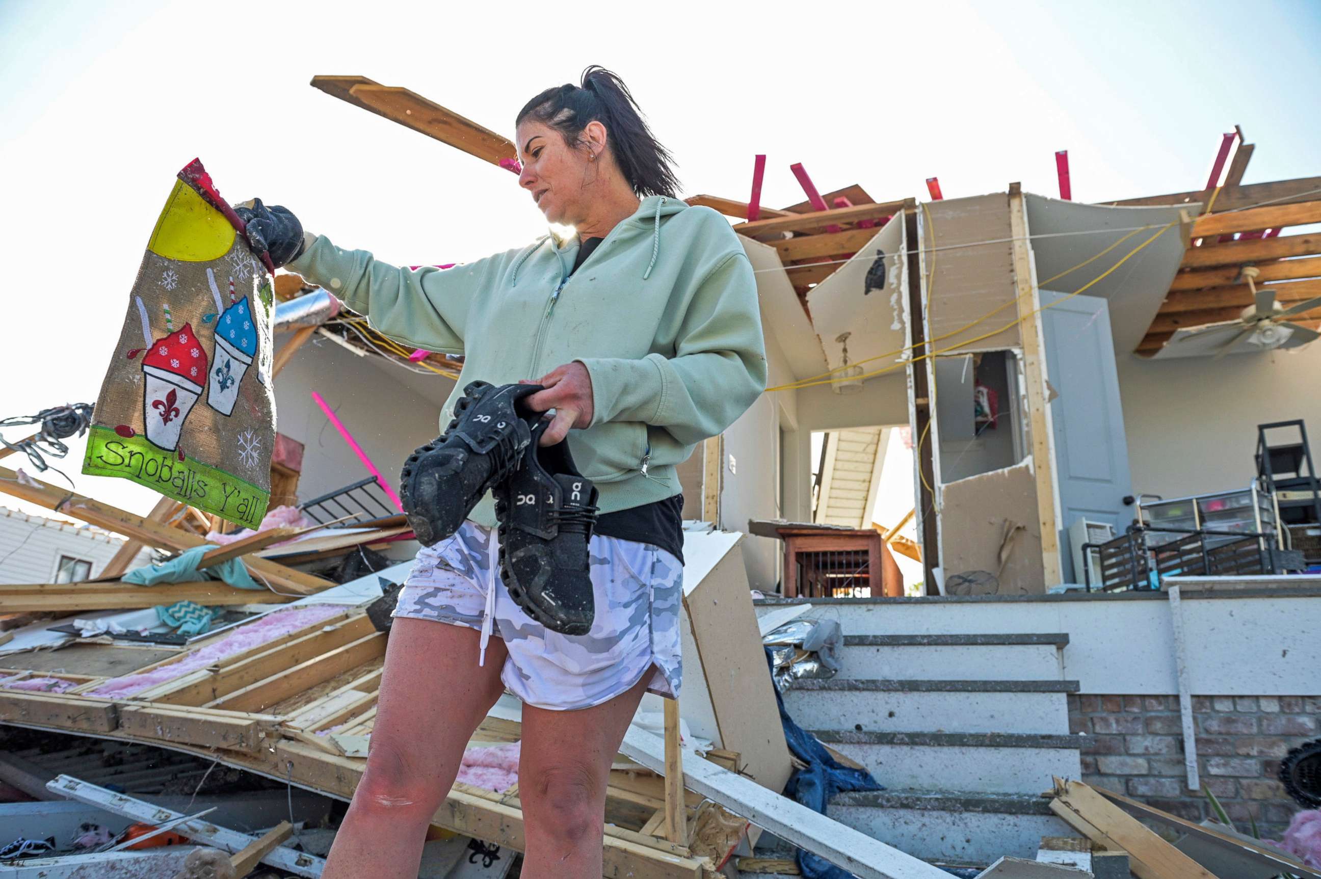 PHOTO: Faye Raimey recovers a garden flag as she looks through the rubble of her tornado damaged home after a tornado touched down in Arabi, La., March 23, 2022.
