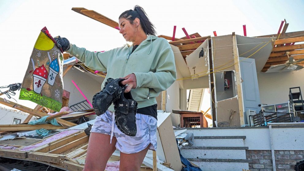 PHOTO: Faye Raimey recovers a garden flag as she looks through the rubble of her tornado damaged home after a tornado touched down in Arabi, La., March 23, 2022.