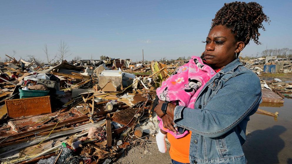 PHOTO: Wonder Bolden cradles her year-old granddaughter Journey Bolden as she surveys the remains of her mother's tornado demolished mobile home in Rolling Fork, Miss., Mar. 25, 2023.