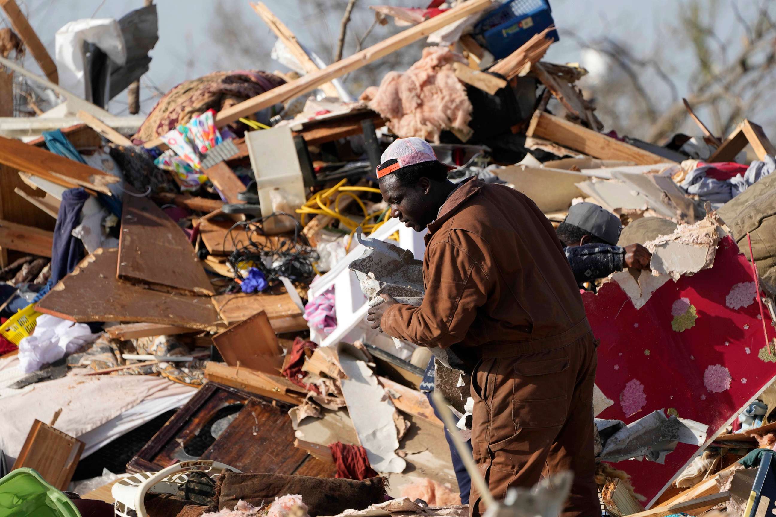 PHOTO: A resident looks through the piles of debris, insulation, and home furnishings to see if anything is salvageable at a mobile home park in Rolling Fork, Miss., Saturday, Mar. 25, 2023.