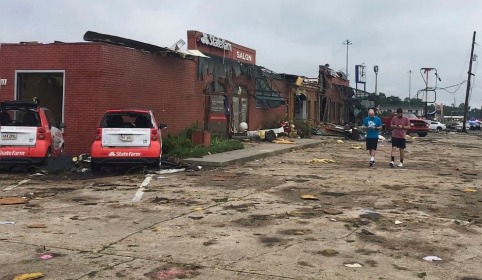 PHOTO: A pair of men walk though the parking lot of a strip mall that was destroyed by a deadly tornado that tore through the northern Louisiana city of Ruston early Thursday, April 25, 2019.