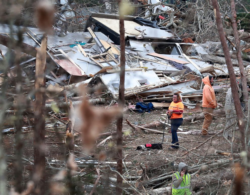 PHOTO: A woman and her dog make their way through the wreckage of shattered homes, March 4, 2019, as rescue workers, residents and volunteers sift through the debris following a  tornado, in Beauregard, Ala.