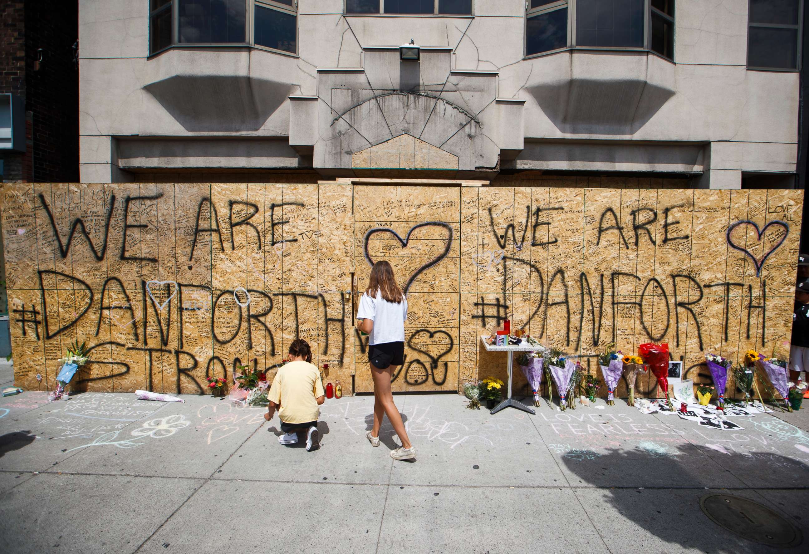 PHOTO: People write messages on a makeshift memorial, July 24, 2018, in Toronto, for the victims of Sunday's shooting.