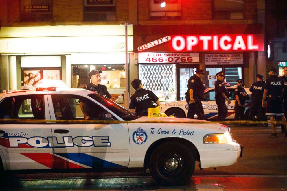 PHOTO: Toronto Police officers walk the scene at Danforth St. at the scene of a shooting in Toronto, July 23, 2018.