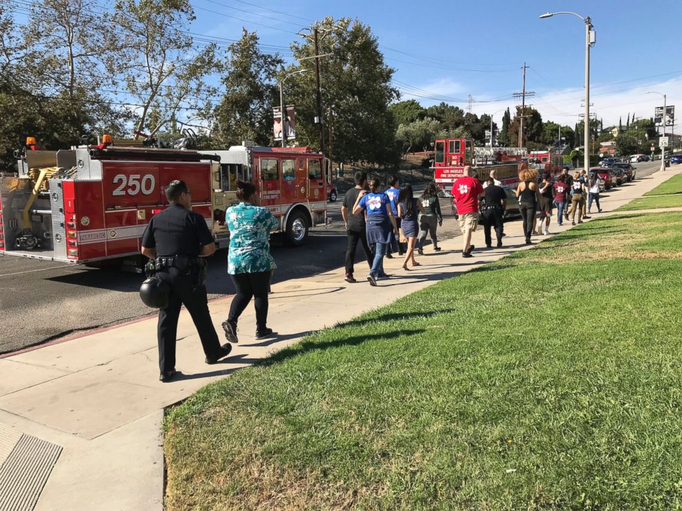 A Los Angeles Police Department officer escorts Trader Joe's employees to the Silver Lake Community Church, a block away from their Trader Joe's store in Los Angeles Saturday, July 21, 2018. 