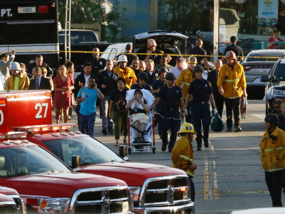 Los Angeles officials escort a woman being evacuated by emergency personnel after a gunman held hostages inside a Trader Joes store in Los Angeles Saturday, July 21, 2018.