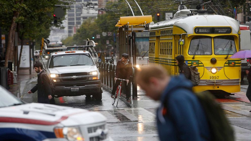 PHOTO: A cyclist waits at a stoplight surrounded by cars, buses and pedestrians during the morning commute on Market Street in San Francisco on June 10, 2015.