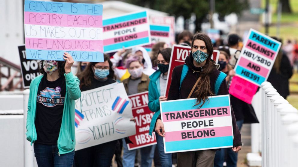 PHOTO: Protesters march with signs in support of transgender and transgender youth rights march around the Alabama State House in Montgomery, Ala., March 2, 2021.