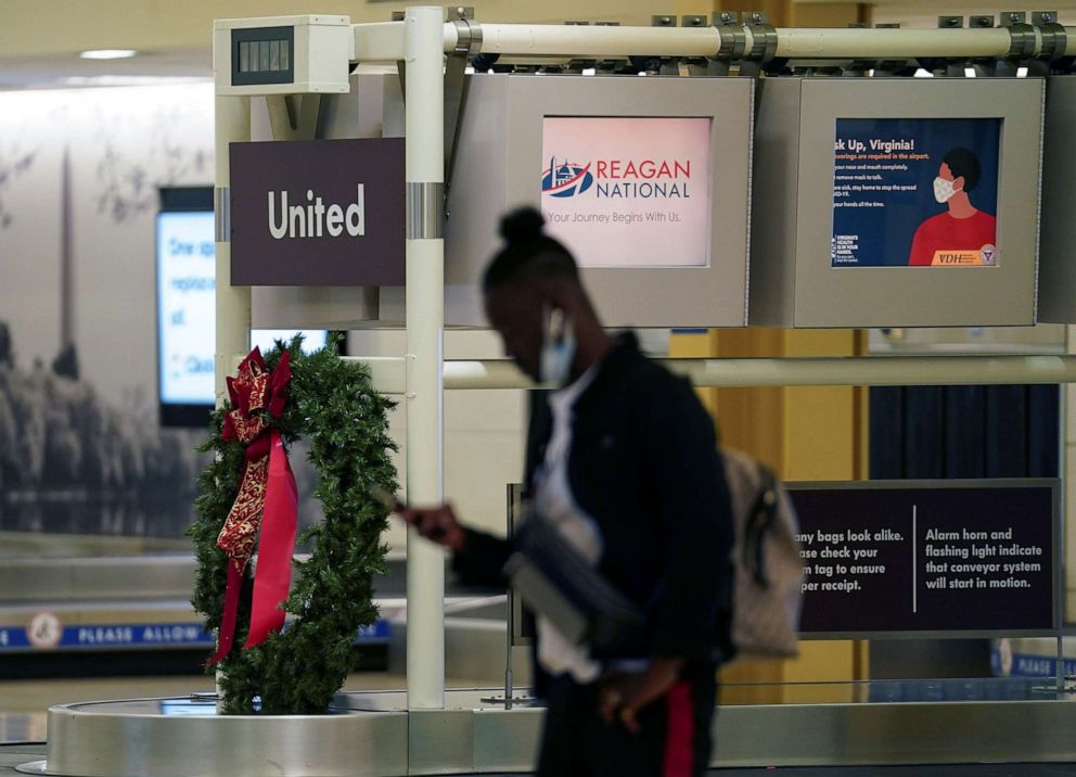 PHOTO: A man checks his phone next to a baggage carousel adorned with a Christmas wreath at Ronald Reagan Washington National Airport, in Arlington, Va., Dec. 22, 2020. 