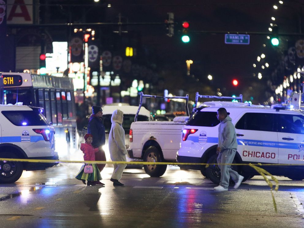 PHOTO: Trick-or-treaters walk past a crime scene in the 3700 block of West 26th Street in Chicago, where a 7-year-old girl was shot while trick-or-treating on Thursday, Oct. 31, 2019.