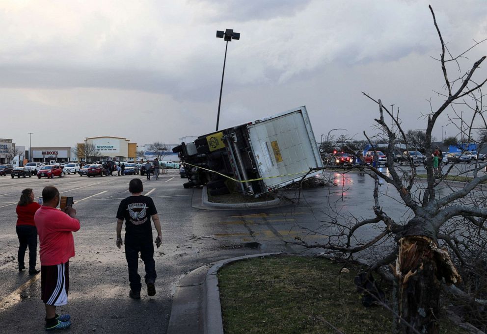 PHOTO: People look at an overturned truck in a parking lot after a storm system touched down in Round Rock, Texas, March 21, 2022.