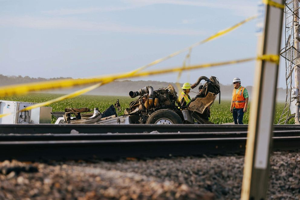 PHOTO: Workers chat behind the remnants of the vehicle where an Amtrak train derailed on June 27, 2022, in Mendon, Mo.