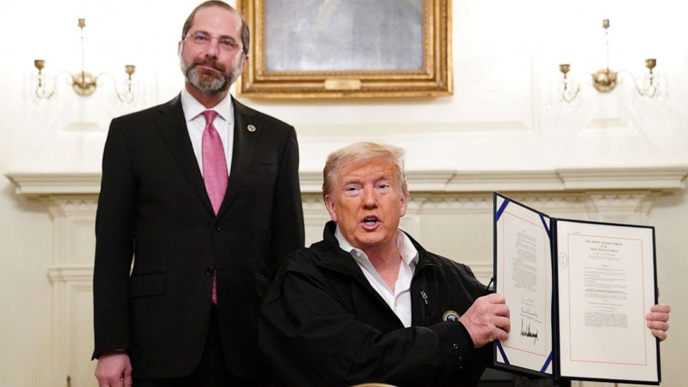 PHOTO: President Donald Trump holds up an eight billion ISD emergency funding bill to combat COVID-19 after signing it as Health and Human Services Secretary Alex Azar looks on in the Diplomatic Room of the White House, in Washington, on March 6, 2020.
