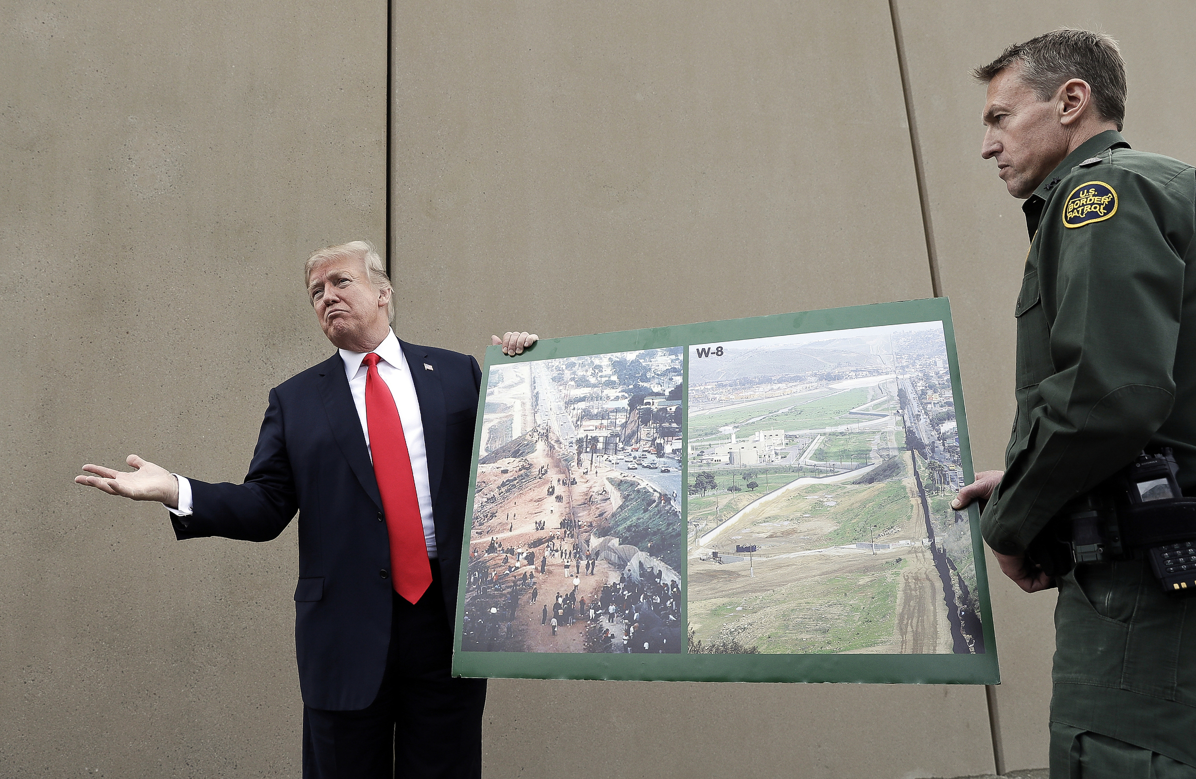 PHOTO: In this March 13, 2018, file photo, President Donald Trump holds a poster with photographs of the U.S.-Mexico border area as he reviews border wall prototypes in San Diego with Rodney Scott, the U.S. Border Patrol's San Diego sector chief.