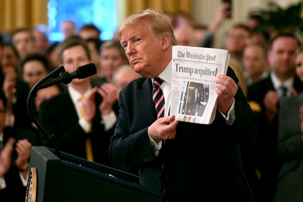 PHOTO: President Donald Trump holds up a newspaper that displays a headline "Acquitted"  while speaking about his Senate impeachment trial at the White House, Feb. 6, 2020.