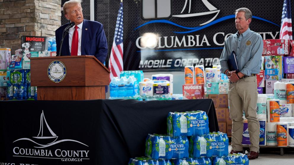 PHOTO: Republican presidential nominee former President Donald Trump speaks as Georgia Gov. Brian Kemp listens at a temporary relief shelter as he visits areas impacted by Hurricane Helene, Oct. 4, 2024, in Evans, Ga.