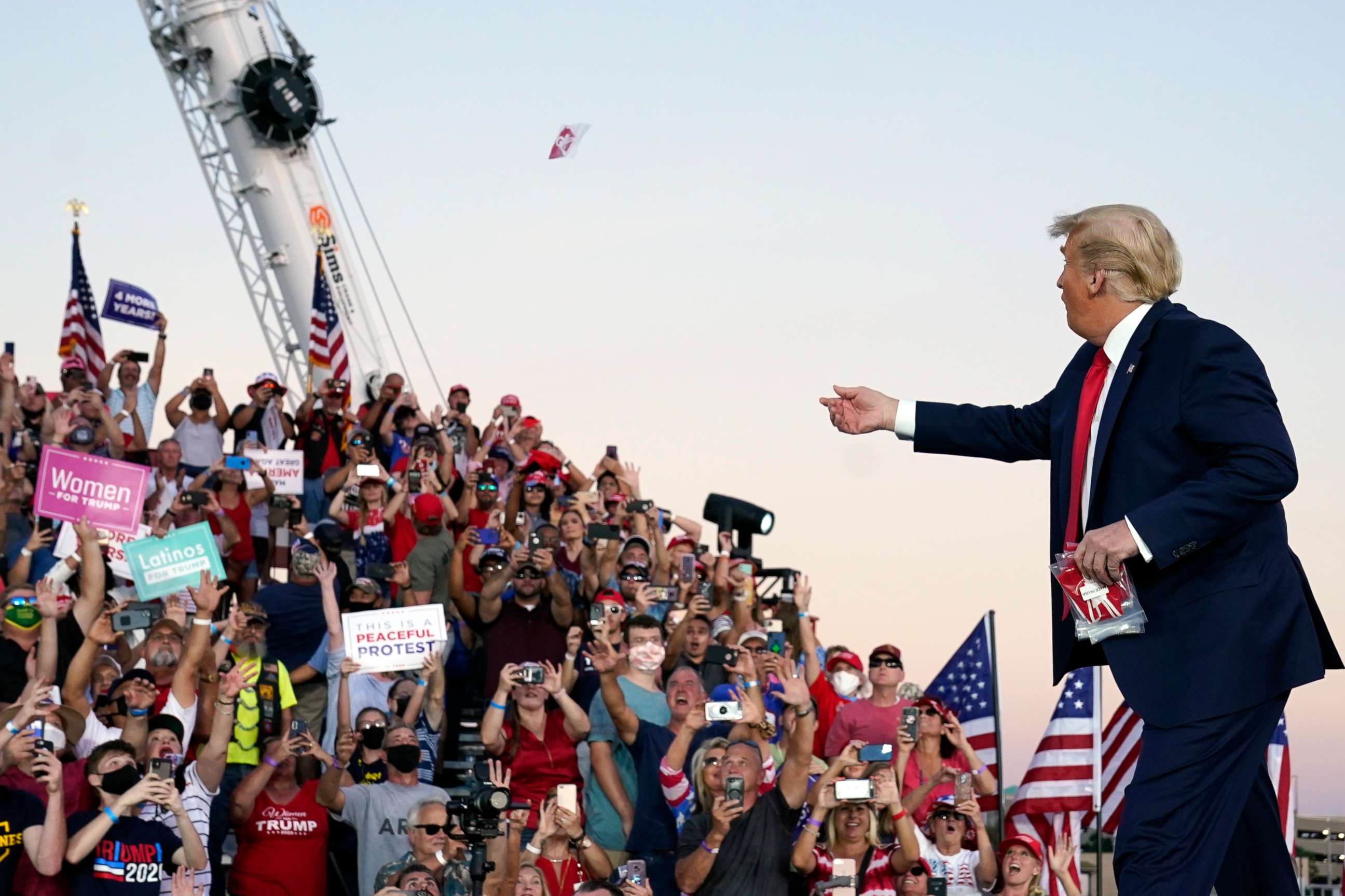 PHOTO: President Donald Trump throw face masks into the crowd as he arrives for a campaign rally at Orlando Sanford International Airport, Oct. 12, 2020, in Sanford, Fla.