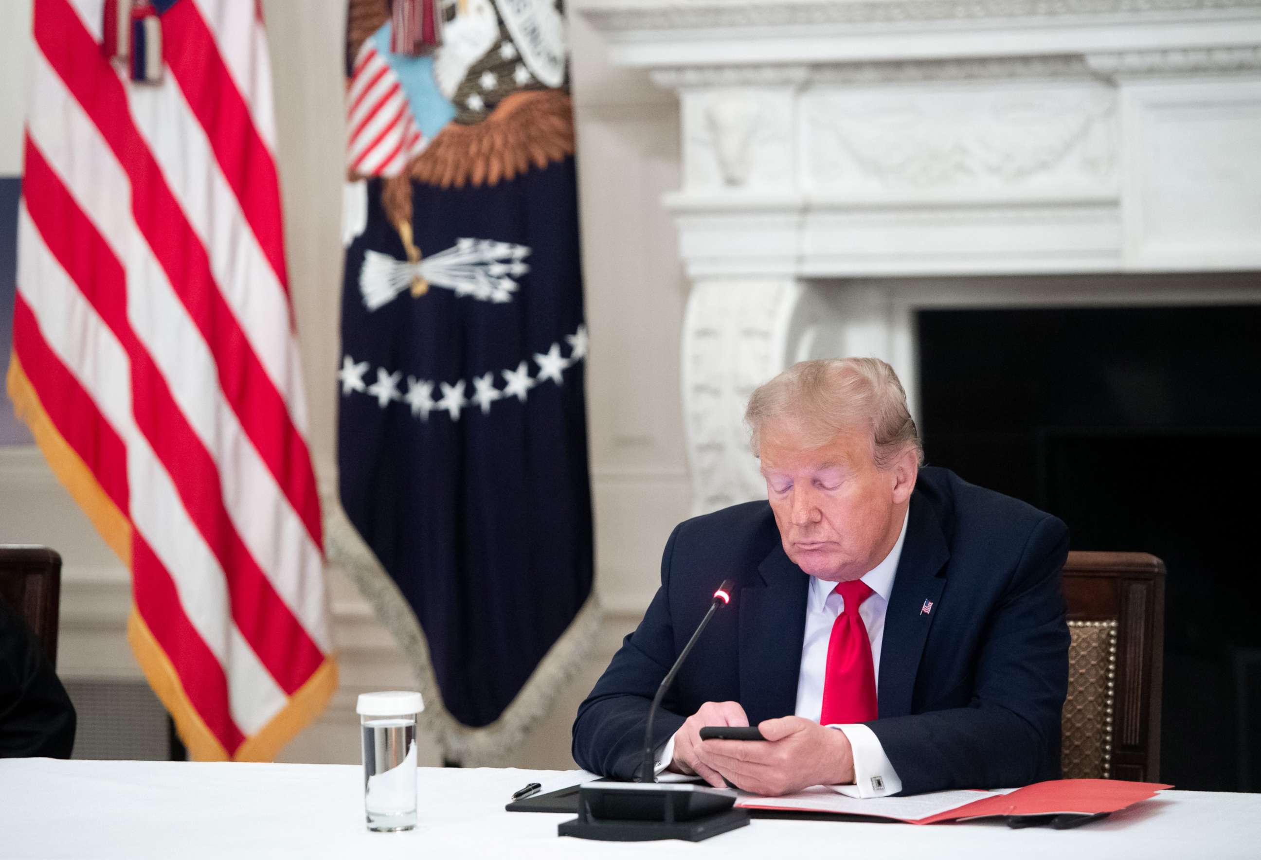 PHOTO: In this June 18, 2020, file photo, President Donald Trump uses his cellphone as he holds a meeting in the State Dining Room of the White House in Washington, DC.