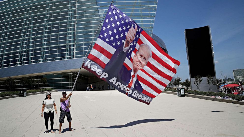 PHOTO: Trump supporters pose for photos with a giant Trump flag outside BOK Center, site of President Donald Trump's first political rally since the start of the coronavirus pandemic, June 18, 2020 in Tulsa, Okla.