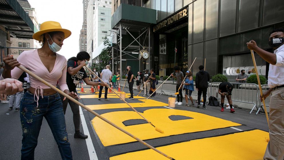 PHOTO: Azia Toussaint, left, participates in the painting of Black Lives Matter on Fifth Avenue in front of Trump Tower, July 9, 2020, in New York.