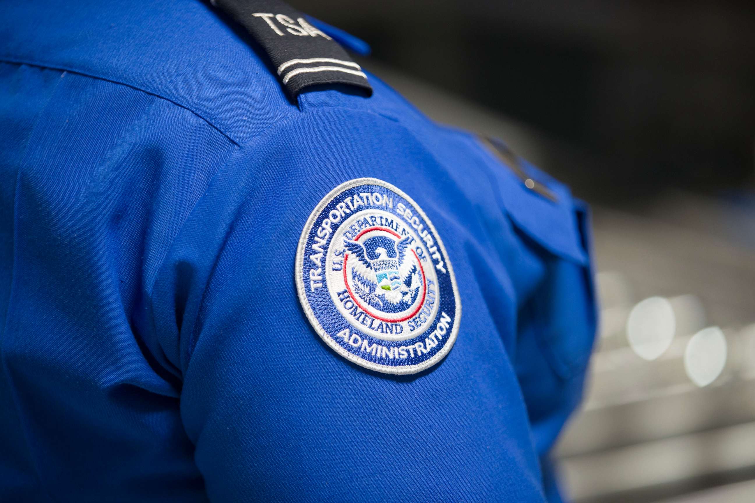PHOTO: A Transportation Security Administration (TSA) agent's patch is seen as she helps travelers place their bags through the 3-D scanner at the Miami International Airport on May 21, 2019 in Miami.