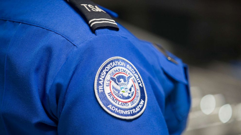 PHOTO: A Transportation Security Administration (TSA) agent's patch is seen as she helps travelers place their bags through the 3-D scanner at the Miami International Airport on May 21, 2019 in Miami.