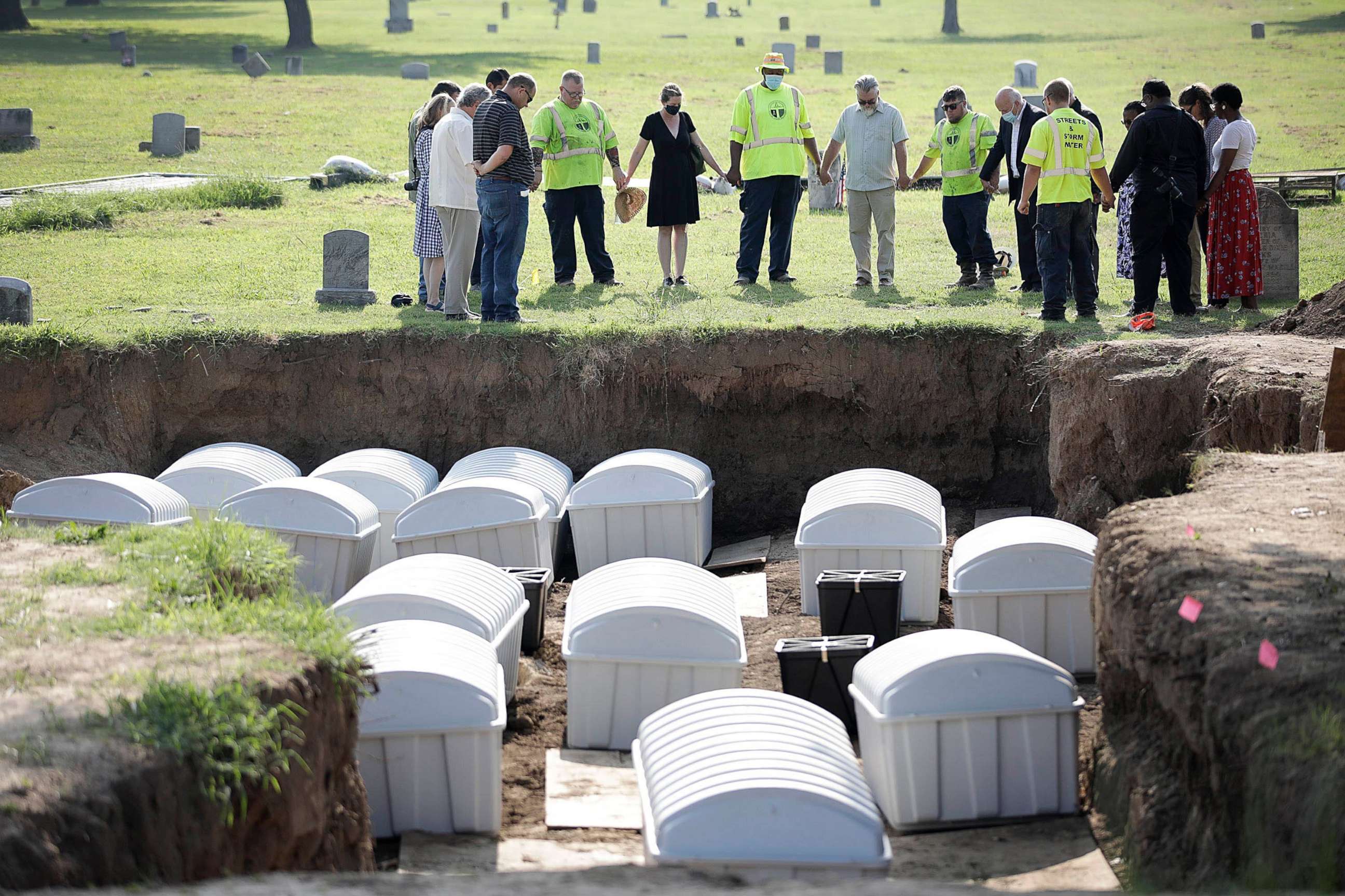 PHOTO: A group prays during a small ceremony as remains from a mass grave are reintered at Oaklawn Cemetery in Tulsa, Okla., July 30, 2021.